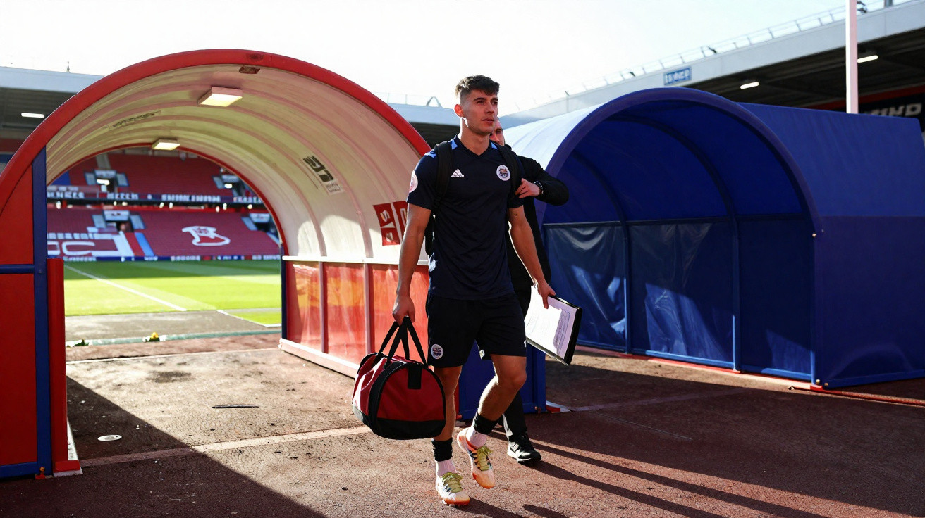 Fußballspieler mit Sporttasche betritt das Spielfeld durch den Tunnel im Stadion bei Tageslicht.