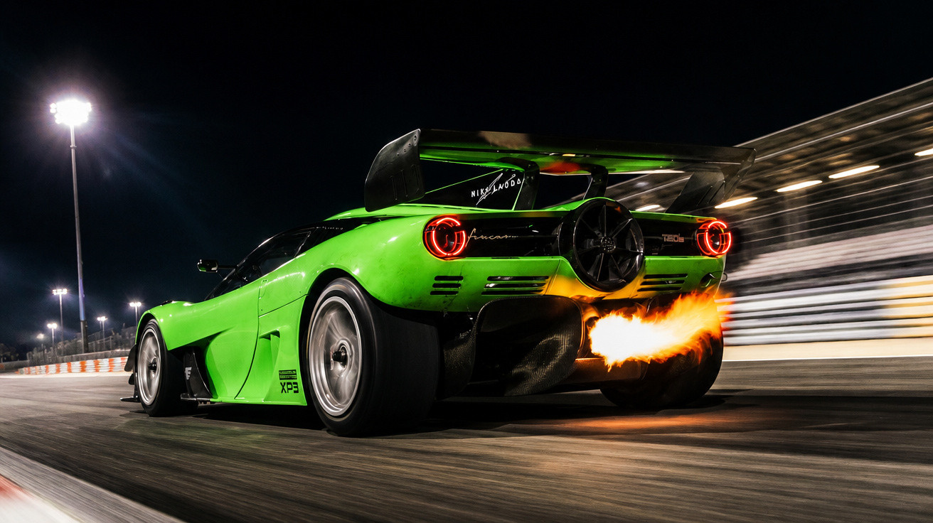 Grüner Rennwagen fährt bei Nacht auf Rennstrecke, Feuerstrahl aus Auspuff sichtbar, schnelle Bewegung.