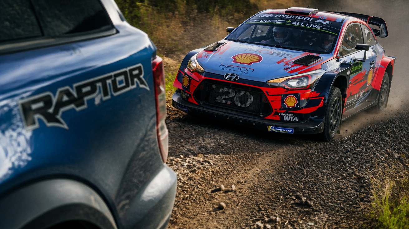 Rallye-Auto Hyundai i20 fährt auf steiniger Schotterpiste, im Vordergrund Teilansicht eines blauen Fahrzeugs mit Raptor-Schri