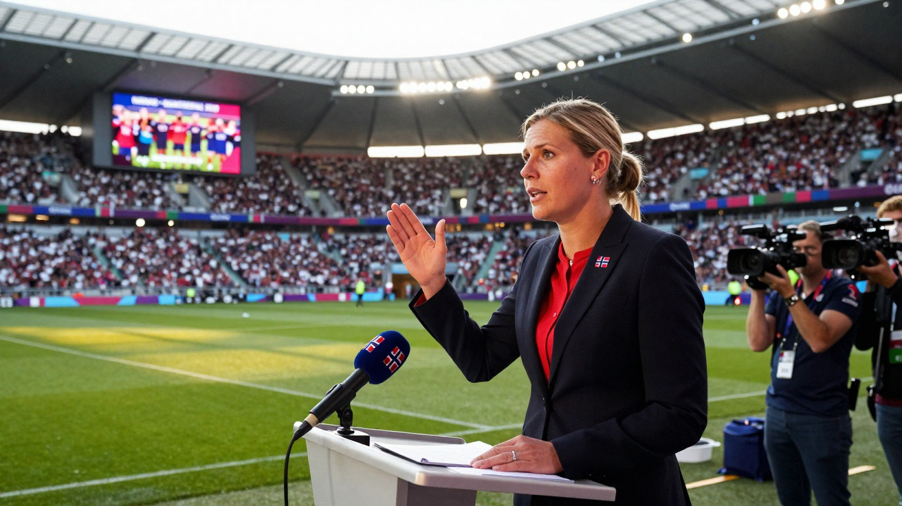 Frau in Anzug hält Rede auf einer Sportarena mit Zuschauern und Kamerateam im Hintergrund.