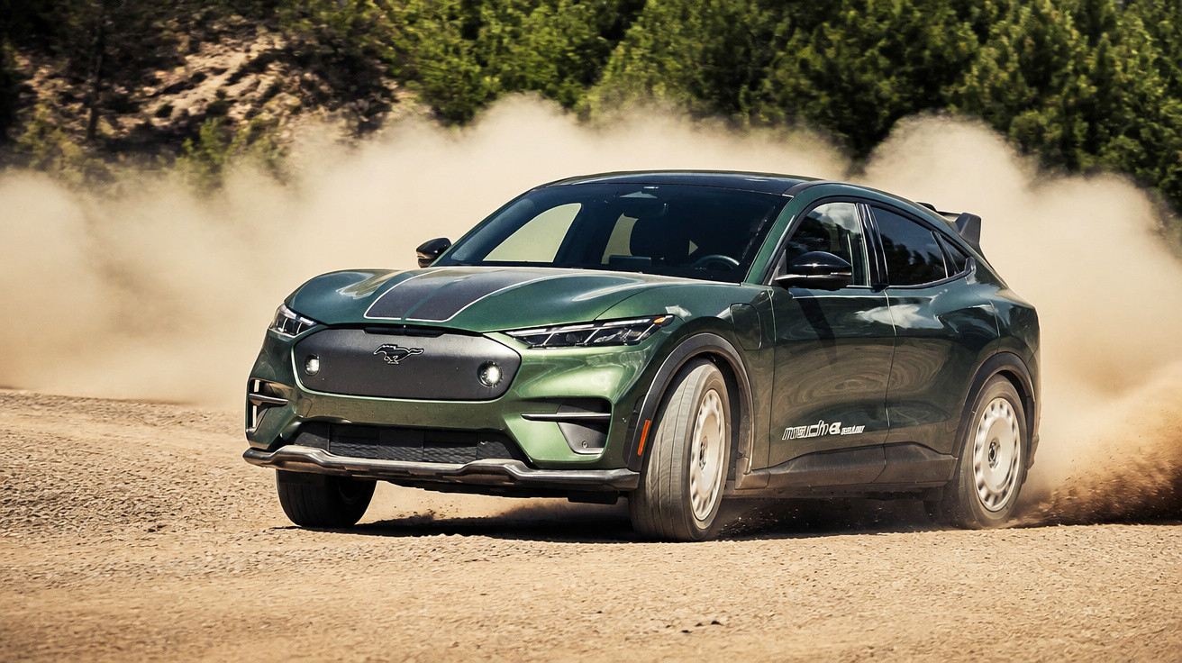 Dunkelgrünes Ford Mustang Mach-E Elektroauto fährt auf staubiger Offroad-Strecke mit Staubwolke im Wald.