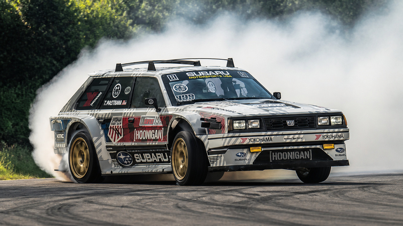 Weißer Subaru Rallye-Auto driftet mit Rauchentwicklung auf Rennstrecke vor grünem Hintergrund.