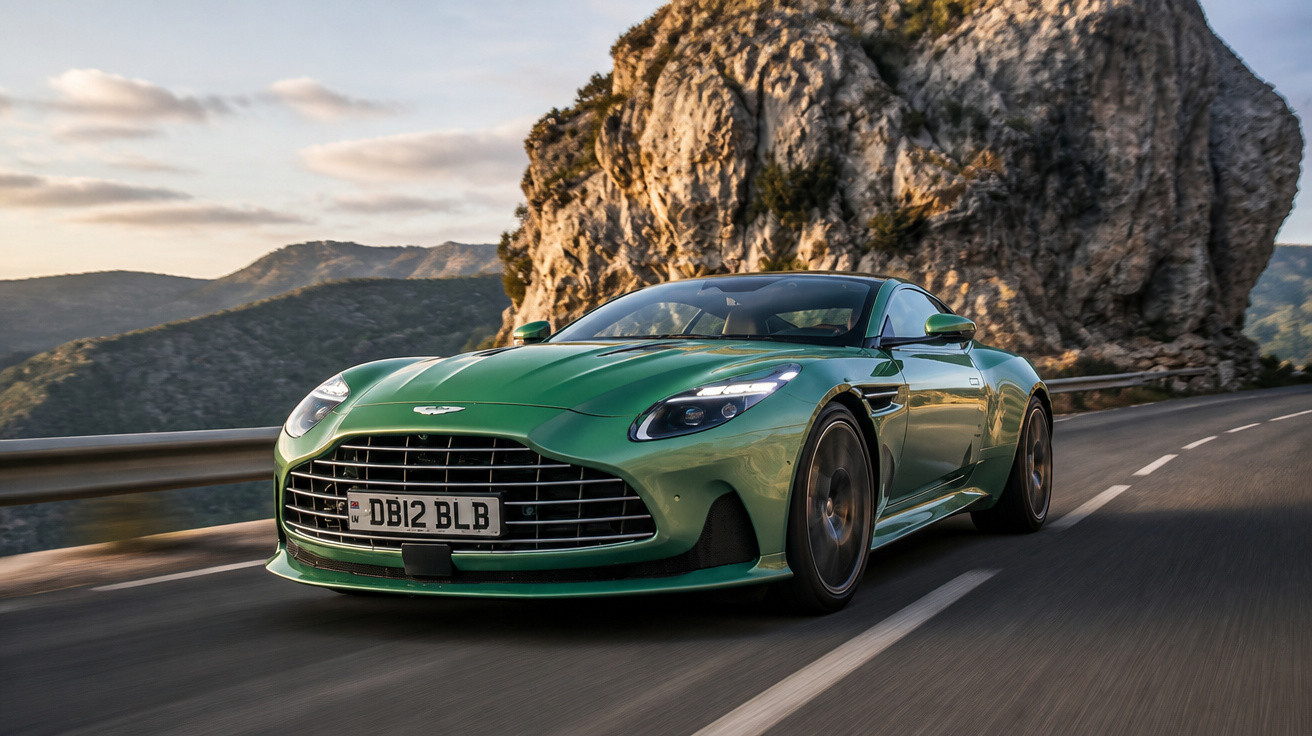 Grüner Aston Martin Sportwagen fährt auf kurviger Straße vor Felsen in sonniger Berglandschaft.