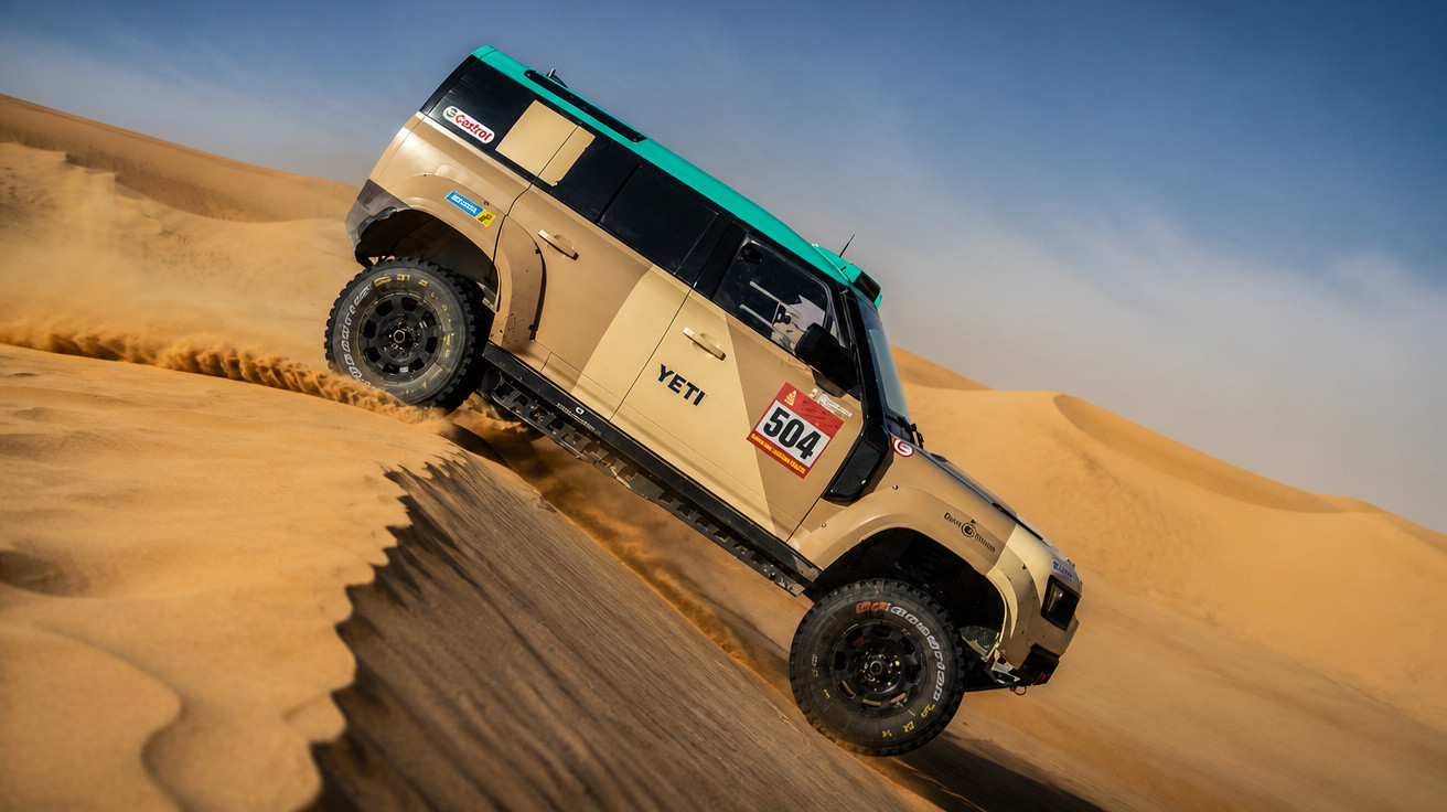 Geländewagen mit Startnummer 504 fährt schräg über Sanddüne in einer Wüstenlandschaft.