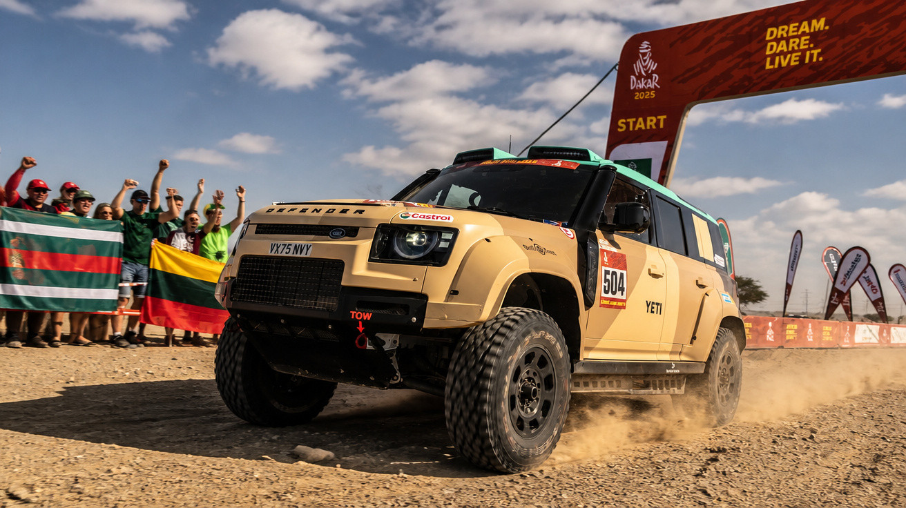 Geländewagen fährt bei Dakar Rallye 2025 über staubigen Startbereich, Zuschauer mit Flaggen jubeln im Hintergrund.